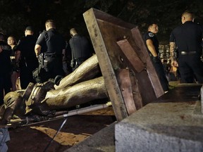 In this Monday, Aug. 20, 2018, file photo, police stand guard after the Confederate statue known as Silent Sam was toppled by protesters on campus at the University of North Carolina in Chapel Hill, N.C.
