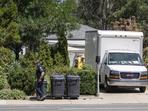 An Aurora, Colo., Police Department officer walks down the sidewalk as another officer in protective gear loads a box truck in front of the home of a man who was shot and killed by police Tuesday, July 31, 2018, in Aurora, Colo.