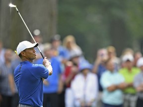 Tiger Woods follows through on his approach shot on the 10th hole during the first round of the Bridgestone Invitational golf tournament at Firestone Country Club, Thursday, Aug. 2, 2018, in Akron, Ohio.