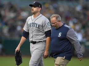 James Paxton of the Seattle Mariners is escorted off the field by a trainer after he was hit with a line-drive at Oakland Alameda Coliseum on August 14, 2018 in Oakland. (Thearon W. Henderson/Getty Images)