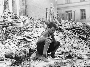 This is a Sept., 1939 file photo of a young Polish boy returns to what was his home and squats among the ruins during a pause in the German air raids on Warsaw, Poland. (AP Photo/Julien Bryan/File)
