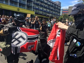Counter protesters tear a Nazi flag, Saturday, Aug. 4, 2018 in Portland, Ore.