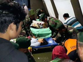 Indonesian soldiers tend to a woman injured in the earthquake at a makeshift hospital in Lombok, Indonesia, Sunday, Aug. 5, 2018.