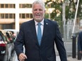 Quebec Liberal Leader Philippe Couillard smiles as he walks to visit his campaign bus Thursday, Aug. 23, 2018 as he launches the provincial election in Quebec City.