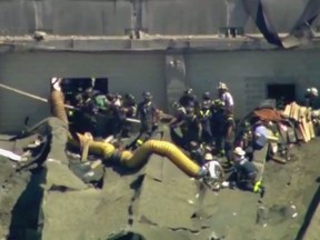 This aerial frame grab from video by WFLD-TV in Chicago shows rescue personnel at the scene where several people were reported trapped inside a Chicago water reclamation plant after a fire and possible explosion caused part of the building's roof to collapse Thursday, Aug. 30, 2018. (WFLD-TV via AP)