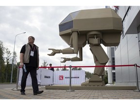 A visitor passes a model of a guided robot-style system presented by the Concern Kalashnikov during the International Military Technical Forum Army-2018 in Alabino, outside Moscow, Tuesday, Aug. 21, 2018.
