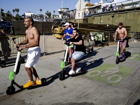 People ride Lime and Bird scooters along the strand in Santa Monica, Calif., on July 1, 2018.