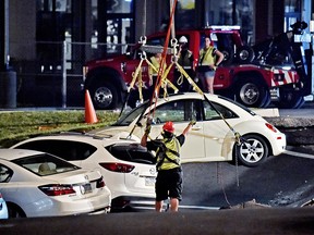 A crane is used to lift vehicles from a sinkhole at Tanger Outlets in Lancaster Pa., shortly after midnight Saturday, Aug. 11, 2018. (Blaine Shahan /LNP/LancasterOnline via AP)