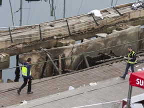 Two police officers work at the scene the day after an oceanside boardwalk collapsed during a nighttime concert in Vigo, Spain, Monday, Aug. 13, 2018. Authorities say the oceanside boardwalk collapsed around midnight Sunday at the closing event of a three-day festival, injuring 313 people, five of them seriously.