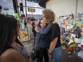 In this July 31, 2018 photo, MaryLinda Moss and Lynne Westafer, right, hug at a memorial outside the Trader Joe's in Silver Lake neighborhood of Los Angeles, where they were held hostage during an hours-long standoff on July 21. (Allen J. Schaben/Los Angeles Times via AP)