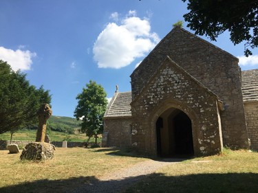 In this July 8, 2018 photo, St Mary's Church in Tyneham stands beneath a brilliant blue sky. The tiny settlement in Dorset, England, was taken over by the British military in late 1943 to provide more land for training, ahead of D-Day. When the residents left, one of them pinned a note to the church door asking that the homes and buildings be treated with respect, as they fully expected to return. But they never did, and Tyneham remains in military hands. The church has been maintained but time and nature have overwhelmed the dwellings, earning Tyneham the nickname of the "ghost village."