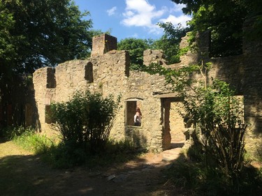 In this July 8, 2018 photo, a visitor inspects the interior of a ruined cottage in the abandoned village of Tyneham, in Dorset, England. The British War Department took over the tiny settlement in late 1943 to provide more land for training ahead of D-Day. The residents have never been allowed back and the now ruined village remains in military hands but is opened to tourists most weekends.