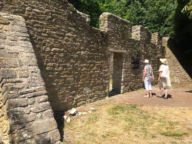 In this July 8, 2018 photo, two visitors pause close to an information board outside a row of ruined cottages in Tyneham, Dorset, south-west England. The residents of the tiny village were compulsorily evacuated in late 1943 to provide extra land for military training, ahead of D-Day, and were never allowed back. In the years since, their homes have fallen apart as weather has rotted the timbers and nature has reclaimed the land. Tyneham is still in military hands but it is open to visitors most weekends.