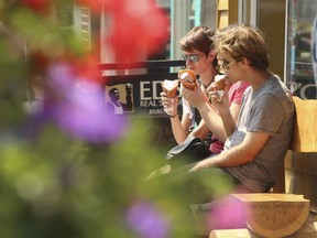 People sit outside a Toronto ice cream parlour  to enjoy a cone in the mid-afternoon on Sunday when the temperature was 33C but felt like 41C with the humidity according to Environment Canada. (Jack Boland/Toronto Sun/Postmedia Network)