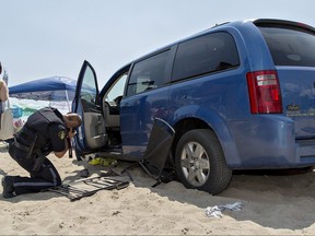 A Norfolk County OPP officer takes photographs of a van which was driven onto the beach at Port Dover, Ont., Saturday Aug. 4, 2018.