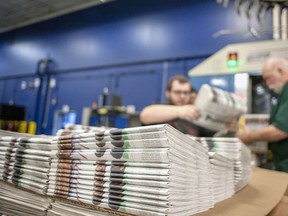 In this April 11, 2018, file photo, production workers stack newspapers onto a cart at the Janesville Gazette Printing & Distribution plant in Janesville, Wis.