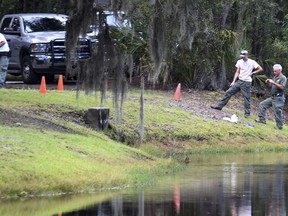 Law enforcement with S.C. Department of Natural Resources take pictures of the site where authorities say Cassandra Cline was dragged into a lagoon by an alligator and killed while trying to save her dog on Monday, Aug. 20, 2018, on Hilton Head Island, S.C.