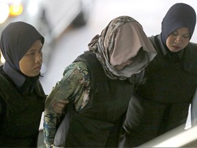 Vietnamese Doan Thi Huong, center, is escorted by police as she arrives for a court hearing at Shah Alam High Court in Kuala Lumpur, Malaysia, Thursday, Aug. 16, 2018. Malaysian court will rule on Thursday whether the two women, Doan and Indonesia's Siti Aisyah, will be acquitted or call their defense, for the brazen assassination of North Korea leader's half brother, Kim Jong Nam.