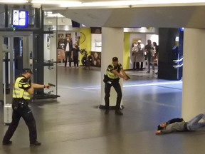 Dutch police officers point their guns at a wounded 19-year-old man who was shot by police after stabbing two people in the central railway station in Amsterdam, the Netherlands, Friday Aug. 31, 2018.