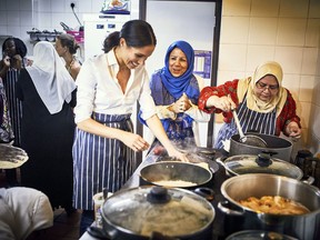 In this undated photograph issued by Kensington Palace on Monday Sept. 17, 2018, Meghan, the Duchess of Sussex cooks with women in the Hubb Community Kitchen at the Al Manaar Muslim Cultural Heritage Centre in London. Set up in the aftermath of the Grenfell Tower fire, the community kitchen has resulted in the publication of "Together: Our Community Cookbook", which the Duchess of Sussex has written the foreword.