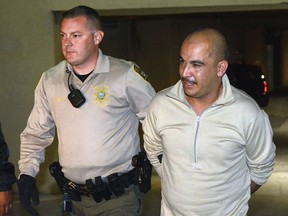 Bernalillo County Sheriff's Office Deputy Daniel Degraff walks Jaime Veleta Jr. to an awaiting car to be booked into Metropolitan Detention Center on murder charges in the death of Danny Baca in 2008, Wednesday, Sept. 5, 2018 in Albuquerque, N.M.