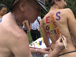 Bicyclist Olivia Neely gets a message advocating for less consumption of fossil fuels painted on her back at the Philly Naked Bike Ride in Philadelphia, Saturday, Sept. 8, 2018. (AP Photo/Dino Hazell)