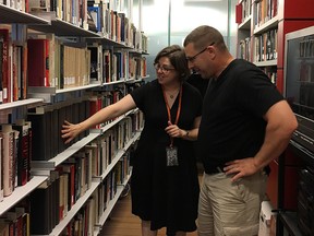 Lindsey Richardson, curator of more than 50,000 artifacts in the reading room below the Sixth Floor Museum at Dealey Plaza, highlights volumes of the famed Warren Commission Report to a visitor. (THE CANADIAN PRESS/Dean Bennett)