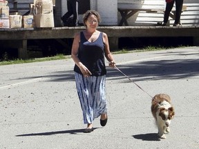 FILE - In this Aug. 24, 2015, file photo, Rabbit Hash Mayor Lucy Lou takes her owner, Bobbi Layne Kayser, on a walk through her jurisdiction, in Rabbit Hash, Ky. The Enquirer reports Rabbit Hash's first female mayor, Lucy Lou, died Monday, Sept. 10, 2018. She was 12, and a dog. (Patrick Reddy/The Cincinnati Enquirer via AP)/The Cincinnati Enquirer via AP) ORG XMIT: OHCIN801