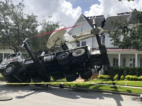 This photo released by the Orlando Fire Department shows a truck carrying a crane tipped over, damaging a house in the Baldwin Park neighborhood of Orlando, Fla., Tuesday, Sept. 4, 2018. (Orlando Fire Department via AP)