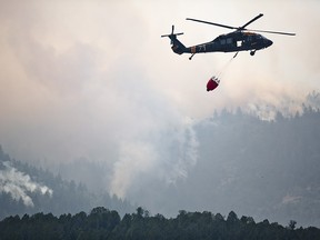 This photo taken Aug. 6, 2018, shows a helicopter returning from performing an air operation on the Coal Hollow Fire near U.S. Highway 6. (Evan Cobb/The Daily Herald via AP)