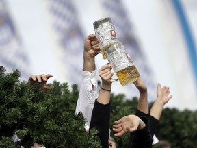 People lift beer glasses during a parade as part of the opening of the 185th 'Oktoberfest' beer festival in Munich, Germany, Saturday, Sept. 22, 2018.