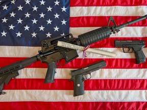 (FILES)This February 4, 2013 file photo illustration in Manassas, Virginia, shows a Colt AR-15 semi-automatic rifle a Colt .45 semi-auto handgun and a Walther PK380 semi-auto handgun and a copy of the US Constitution on top of the American flag.