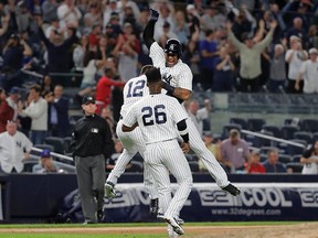 New York Yankees' Aaron Hicks celebrates with teammates Tyler Wade and Andrew McCutchen after hitting an RBI double during the 11th inning of a baseball game against the Baltimore Orioles Saturday, Sept. 22, 2018, in New York.