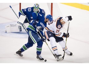 Vancouver Canucks defenceman Ashton Sautner fights for control of the puck with Edmonton Oilers centre Kyle Brodziak as Vancouver Canucks goaltender Anders Nilsson look on during first period NHL pre-season action at Rogers Arena in Vancouver, Tuesday, Sept, 18, 2018.