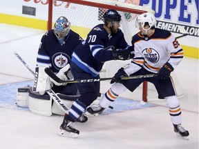 Edmonton Oilers' Kailer Yamamoto (56) tips a shot past Winnipeg Jets' goaltender Connor Hellebuyck (37) as he's checked by Joe Morrow (70) during first period preseason NHL hockey action in Winnipeg, Sunday, September 23, 2018.
