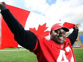 Canadian defensive lineman Mike Labinjo mugs for a photo with a Canadian flag during a light Calgary Stampeders practice at McMahon Stadium on Tuesday, June 30. The Stamps were prepping for their Canada-Day season opener the next day against the Montreal Alouettes.n/a ORG XMIT: S10Stamps0