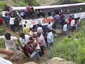 In this grab made from video provided by KK Productions, rescuers pull out passengers from a bus that fell into a gorge in Jagtiyal district of Telangana, India, Tuesday, Sept. 11, 2018. The bus was carrying pilgrims from a Hindu temple in the hills of south India when it plunged off a road  killing several people