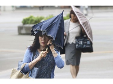 Pedestrians try to hold their umbrellas while struggling with strong winds in Yokohama, near Tokyo, Tuesday, Sept. 4, 2018.
