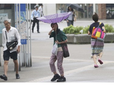 A woman tries to hold her umbrella while struggling with strong winds in Yokohama, near Tokyo, Tuesday, Sept. 4, 2018.