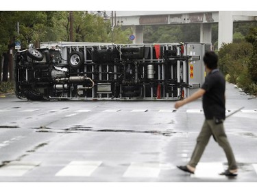 A man looks at a truck overturned following a powerful typhoon in Osaka, western Japan, Tuesday, Sept. 4, 2018.