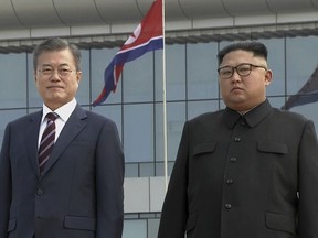 In this image made from video provided by Korea Broadcasting System (KBS), South Korean President Moon Jae-in, left, poses with North Korean leader Kim Jong Un for a photo on the podium upon arrival in Pyongyang, North Korea, Tuesday, Sept. 18, 2018. Moon landed in Pyongyang for his third summit this year with Kim. (Korea Broadcasting System via AP)