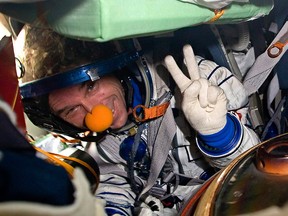 Space tourist Canadian billionaire and clown Guy Laliberte shows a victory sign while sitting inside the Soyuz TMA-14 spacecraft shortly after his landing with the members of the main mission to the International space station, Russian cosmonaut Gennady Padalka and NASA astronaut Michael Barratt, not seen, near the town of Arkalyk, Kazakhstan, on Sunday, Oct. 11, 2009.