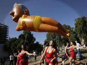 Dancers perform under an inflatable caricature balloon of London Mayor Sadiq Khan as it flies over Parliament Square in London, Saturday, Sept. 1, 2018.