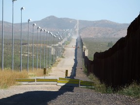In this Nov. 15, 2016, photo provided by Kenneth Madsen, stadium lights atop tall poles oversee a pedestrian barrier stretching for miles along a section of the border wall between Douglas, Arizona, and Agua Prieta, in the Mexican state of Sonora.