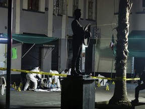 Crime scene workers cover the bodies of victims of a shooting in Garibaldi Plaza, in Mexico City, Friday Sept. 14, 2018.