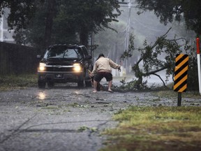 A man moves a large tree limb that downed power lines as the hurricane-turned-tropical storm Florence hit the Cherry Grove community in North Myrtle Beach, S.C., Friday, Sept. 14, 2018.