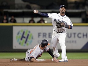 Seattle Mariners shortstop Jean Segura, right, throws to first base after forcing out Baltimore Orioles' Joey Rickard at second base Monday, Sept. 3, 2018, in Seattle.