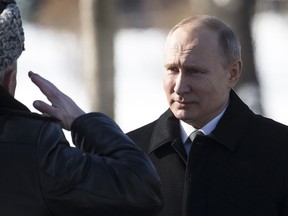 In this Friday, Feb. 23, 2018 file photo, Russian President Vladimir Putin, right, listens to the defence minister as he arrives to attend a wreath-laying ceremony at the Tomb of the Unknown Soldier in Moscow, Russia.