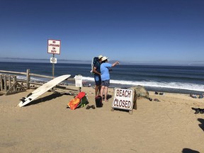 Two people look out at the shore after a reported shark attack at Newcomb Hollow Beach in Wellfleet, Mass,  on Saturday, Sept. 15, 2018.