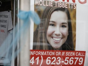 FILE - In this Aug. 21, 2018, file photo, poster for missing University of Iowa student Mollie Tibbetts hangs in the window of a local business in Brooklyn, Iowa. Tibbetts was reported missing from her hometown in the eastern Iowa city of Brooklyn in July 2018. Her body was found Aug. 21, 2018 and Cristhian Bahena Rivera, a Mexican national was charged in her killing. Rivera was known for years by another name on the dairy farm where he worked: John Budd. The name under which worked for the last four years was confirmed by three people with knowledge of his employment history, who spoke on condition of anonymity.